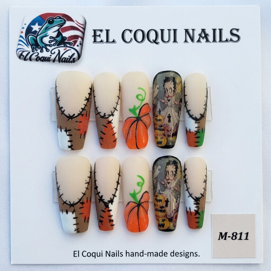A set of Halloween-themed press-on nails by El Coquins, featuring a mix of stitched beige fingernails, orange pumpkins with green stems, and a spooky cartoon character nail. The product is displayed on its original white backing card with product codes 'M-911' and 'M-490' visible.