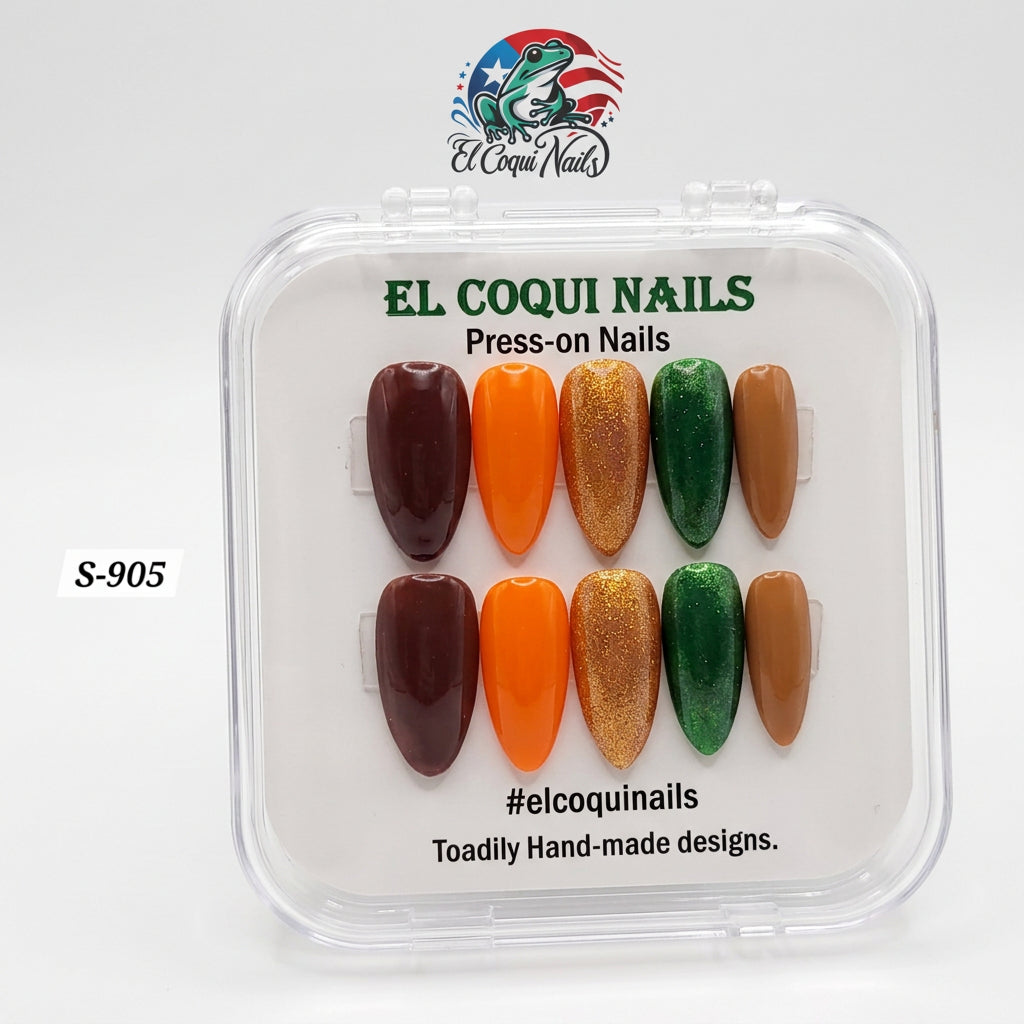 A clear plastic clamshell case of El Coqui Nails press-on nails on a white surface. The nails are arranged in two rows of six and include shades of dark brown, bright orange, metallic gold glitter, emerald green, and tan.