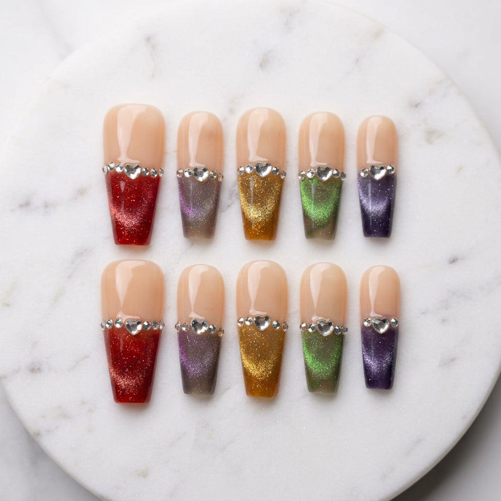 A set of false press-on nails on a backing card labeled EL COQUINAILS, displayed on a white surface. The nails feature a nude beige base with rhinestone trim and come in multiple colors including red, orange, gold, green, purple, and pink.