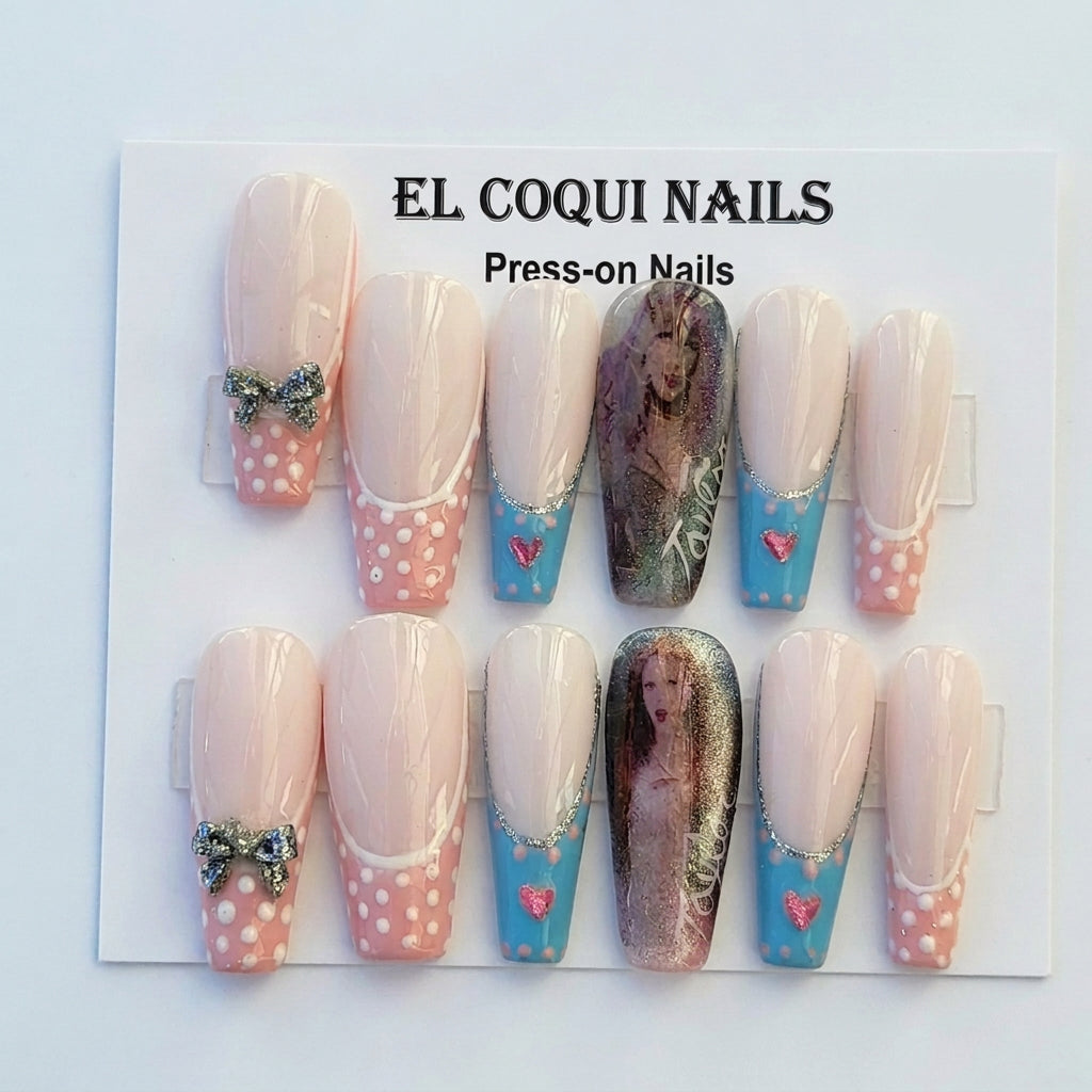 A 10-piece press-on nail set by El Coqui Nails, featuring a mix of pastel pink and blue designs with white polka dots, rhinestone bows, and one pair with a gothic-style printed graphic. The nails are displayed on their original white backing card, which features the brand name 'EL COQUI NAILS' at the top.