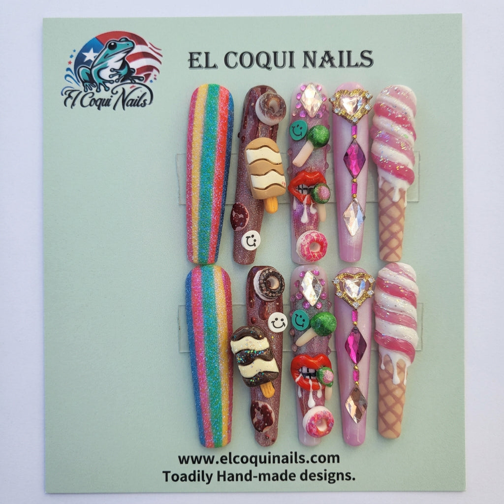 A set of handmade, highly decorated press-on nails displayed on a green backing card. The nails feature various whimsical designs including rainbow stripes, chocolate brownies, ice cream cones, donuts, and candy accents.